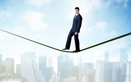 City scape, tall buildings and clouds on clear blue sky with business person balancing on black rope concept