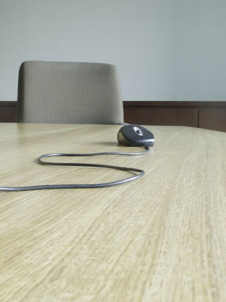Computer mouse with snaking cable near chair at end of conference table