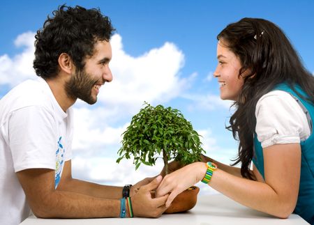 beautiful happy couple holding hands around a little bonsai tree