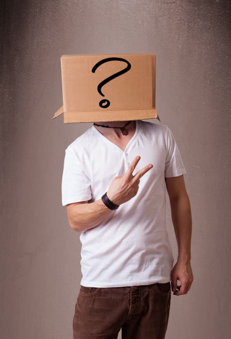 Young man standing and gesturing with a cardboard box on his head with question mark