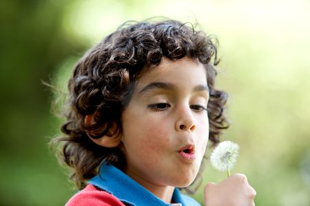 Kid blowing a dandelion at the park