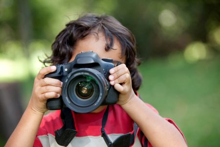 Little boy playing with a camera outdoors