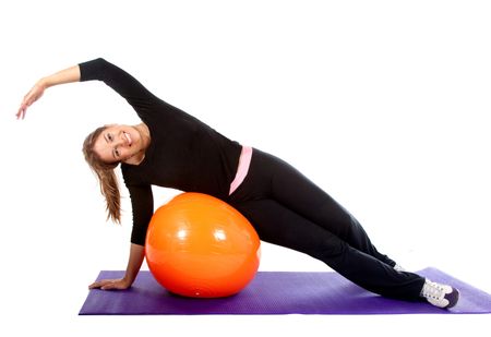 Woman exercising with a pilates ball - isolated over a white background