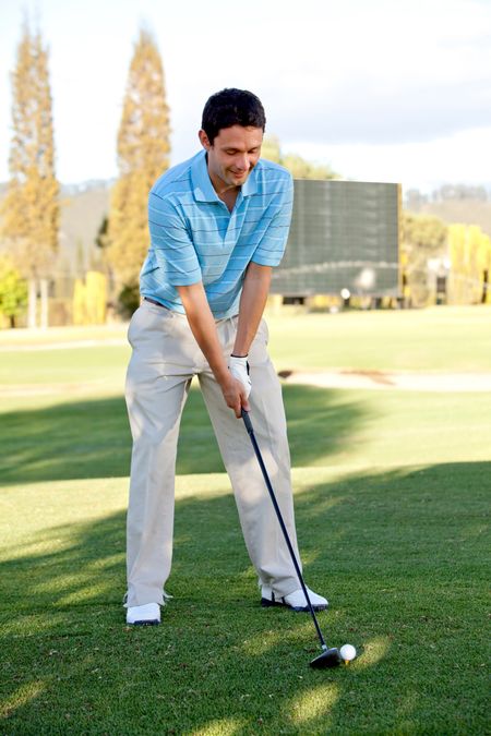 Young man playing golf at the course ready to hit the ball