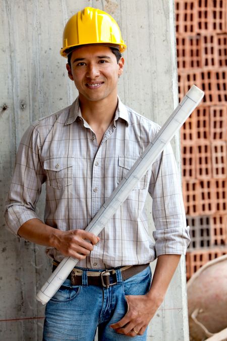 male architect at a construction site holding blueprints