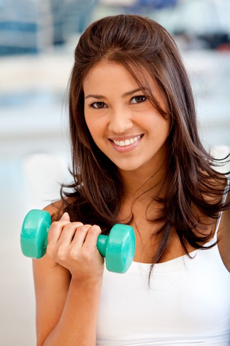 Woman at the gym lifting a free-weight and smiling