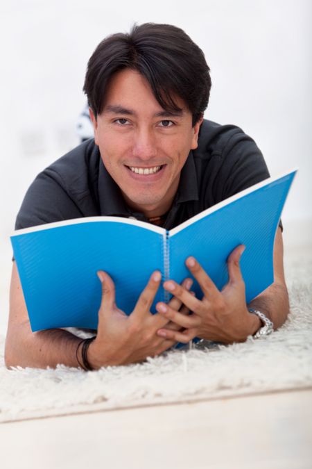 Man lying on the floor reading a book and smiling