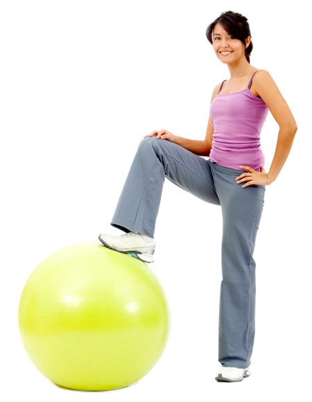 Woman standing with a leg over pilates ball - isolated over white