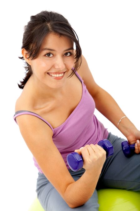 Woman exercising with weights and a pilates ball isolated over a white background