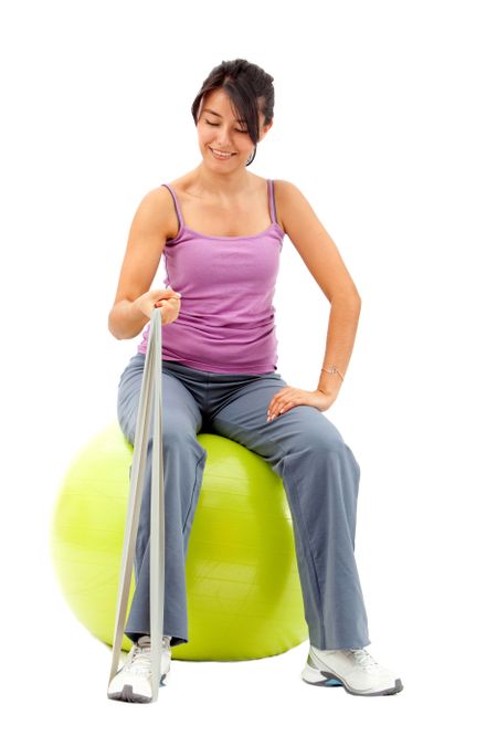 Woman exercising with a pilates ball and a stretch band - isolated