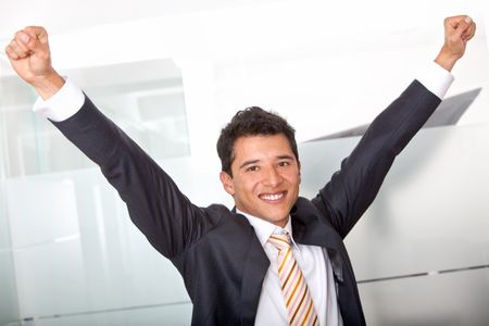 Successful business man at the office with arms up