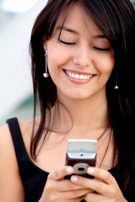 Business woman texting on her mobile phone and smiling