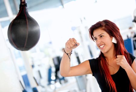Woman boxing at the gym hitting a punch ball