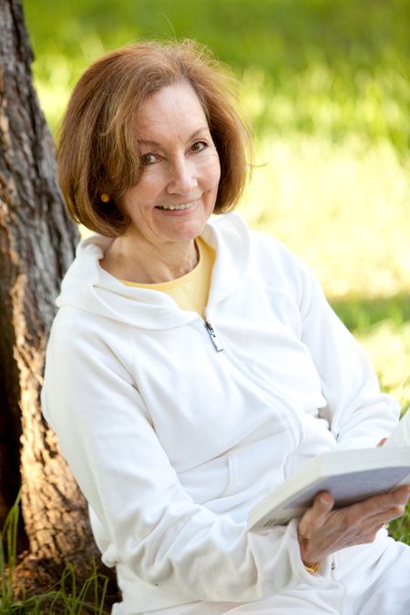 casual-woman-reading-book-outdoors-smiling-51318271 Casual woman reading a book outdoors and smiling