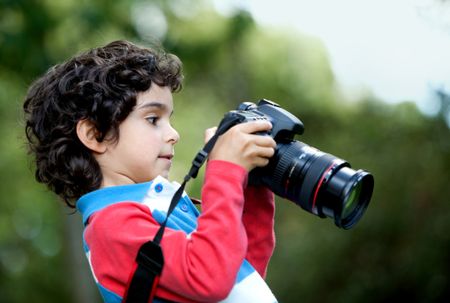 Boy taking pictures and playing with a camera outdoors