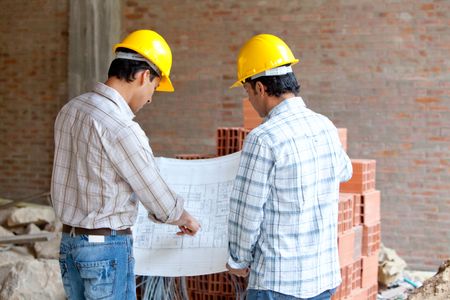 Architects at a construction site looking at blueprints