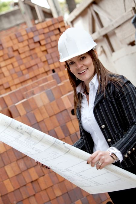 Female engineer at a construction site holding blueprints
