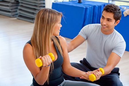 Woman and her trainer exercising at the gym