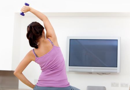 Woman exercising at home in front of the tv