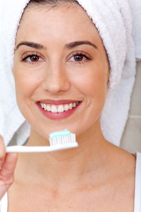 Woman holding a toothbrush in front of her face and smiling
