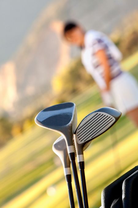 Golf clubs with a blurry female player on the background
