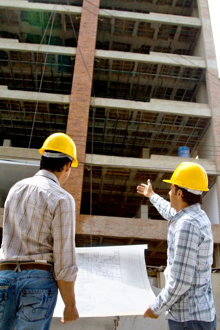 Architects at a construction site looking at blueprints