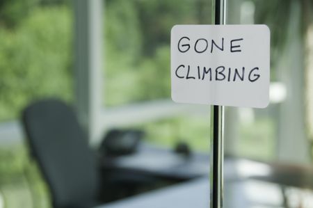 Hand-lettered sign on glass door to office: GONE CLIMBING (shallow field of depth)