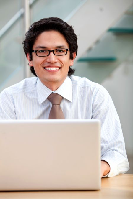 business man looking happy on a laptop in his office