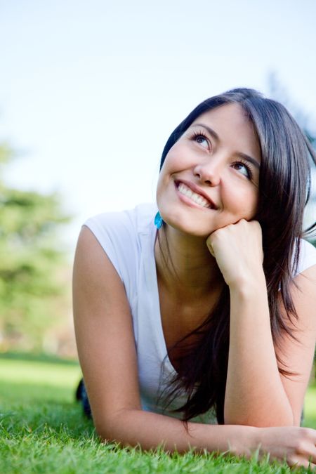 casual pensive woman portrait smiling and looking happy outdoors