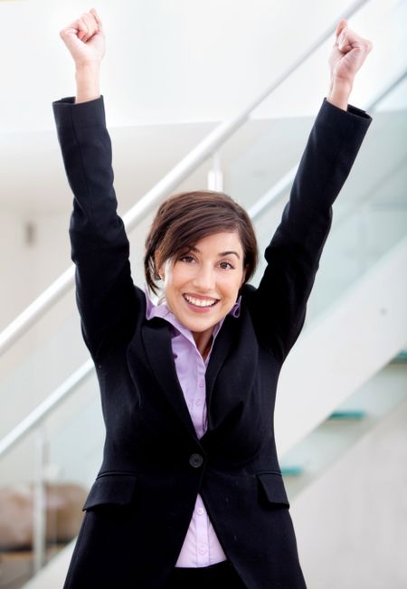 business woman full of success with her arms up at the office