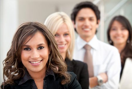 Business woman smiling with her team behind her at the office