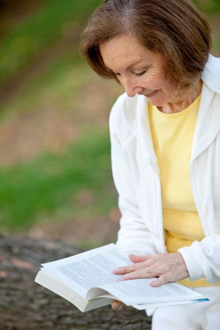 Senior woman reading a book at the park