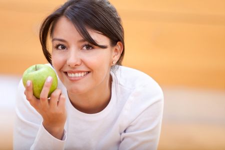 casual woman smiling with an apple at home