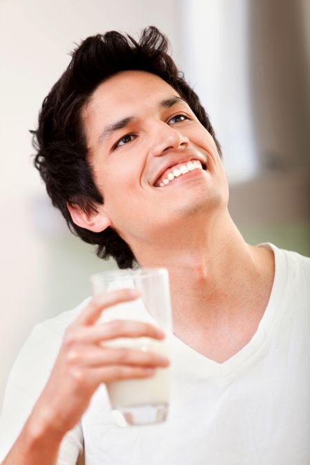 Casual man smiling and drinking a glass of milk