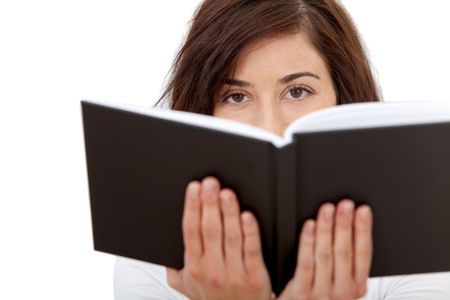 casual woman holding a book in front of her face isolated over a white background