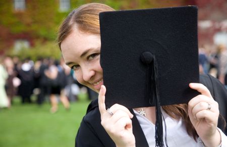 portrait of a female graduating at university hiding behind her hat