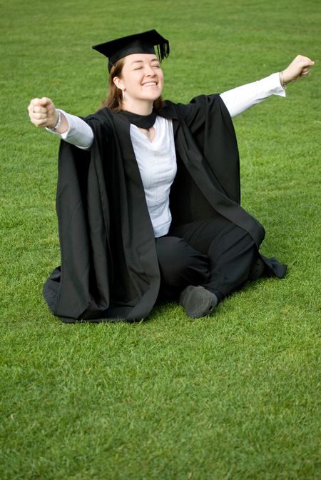 portrait of a female graduating at university looking very happy with her arms up