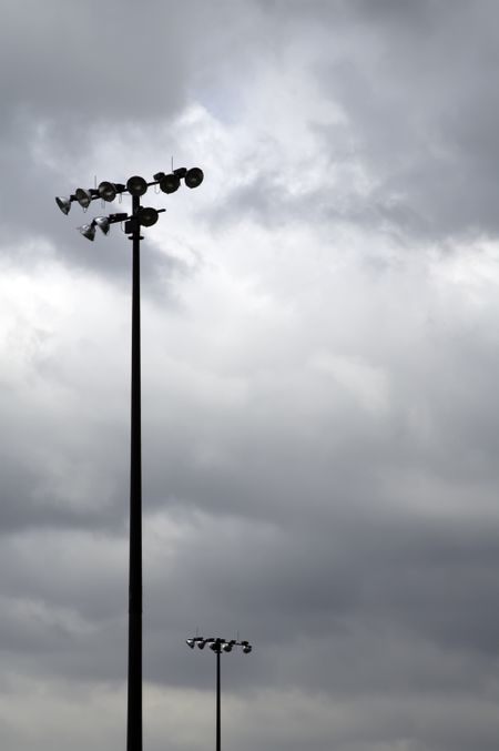 Light poles above baseball fields in public park, cloudy sky, full daylight
