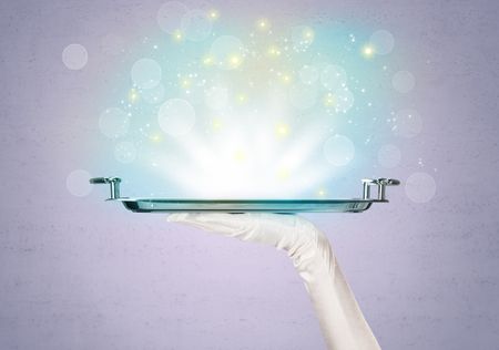 Glowing lights glitter on silver plate served on tray by waiter hand in white elegant glove in front of purple background