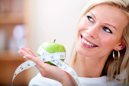 Healthy eating woman holding an apple with a measuring tape around it