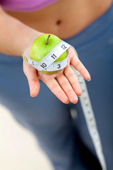 Woman holding an apple with a measure tape around it