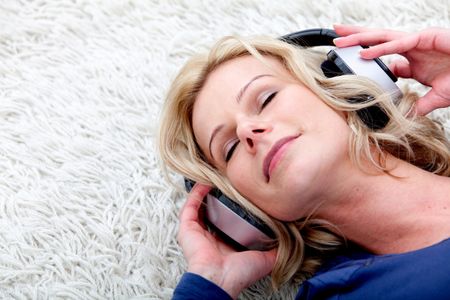 Beautiful woman lying on the floor listening to music
