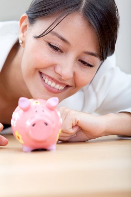 Business woman looking at a a piggybank and smiling