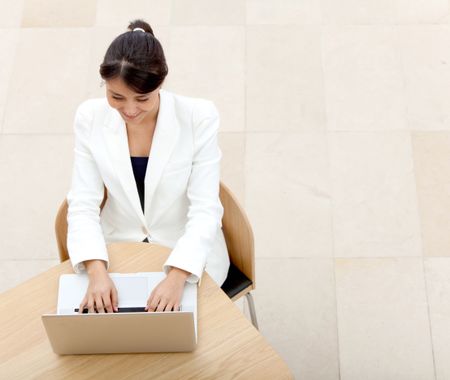 Business woman working on a laptop at the office and smiling