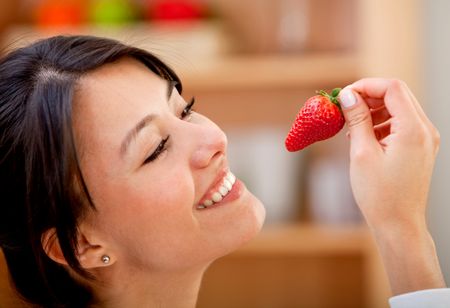 Beautiful woman about to eat a strawberry and smiling