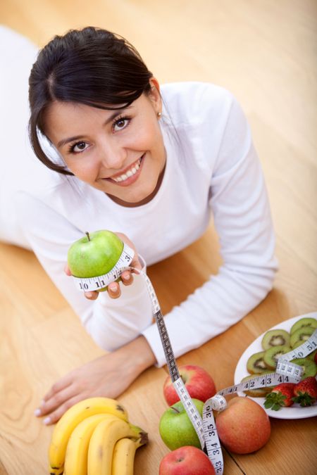 Healthy eating woman lying on the floor with fruits