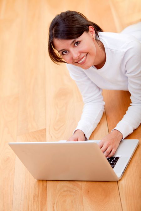 Woman lying on the floor with a laptop and smiling