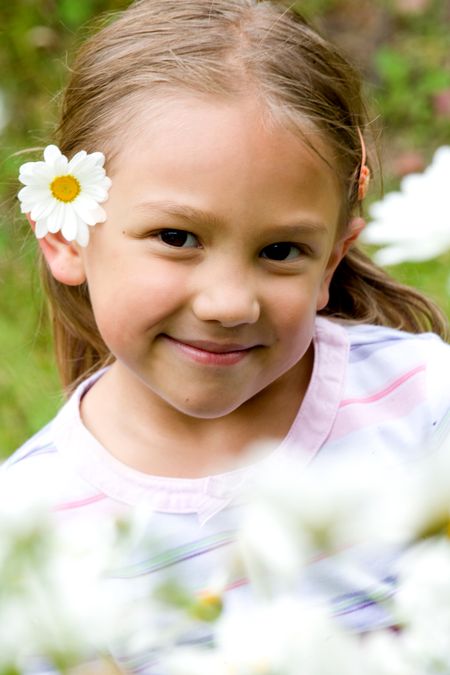 beautiful little girl portrait with flowers in front of her and on her ear