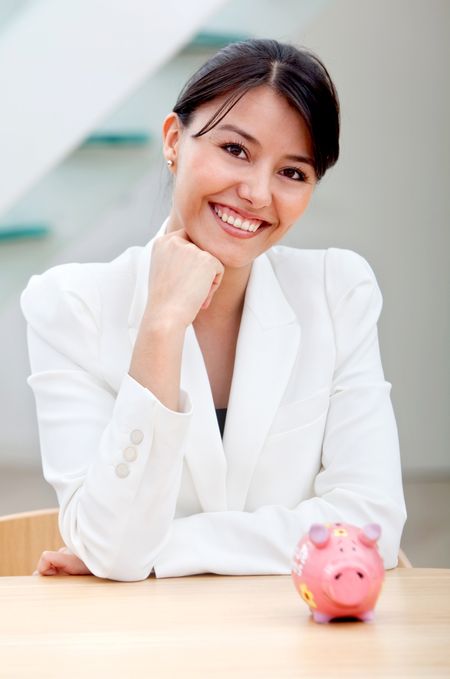 Business woman at the office with a piggybank on the desk