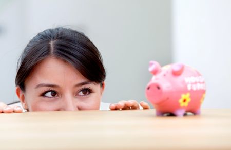 Business woman at the office looking at a piggybank on the desk